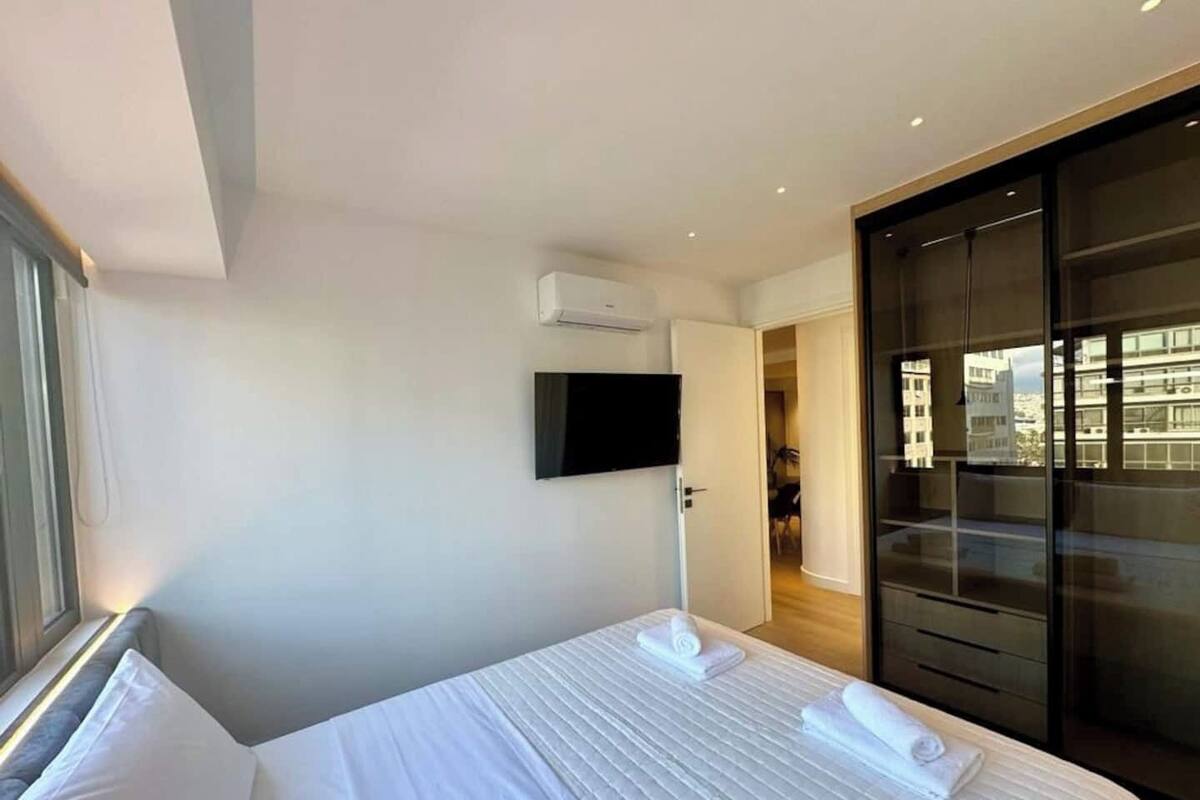 Une chambre d’hôtel moderne dotée d’un grand lit, d’une télévision à écran plat, d’une armoire et offrant une vue sur la ville.