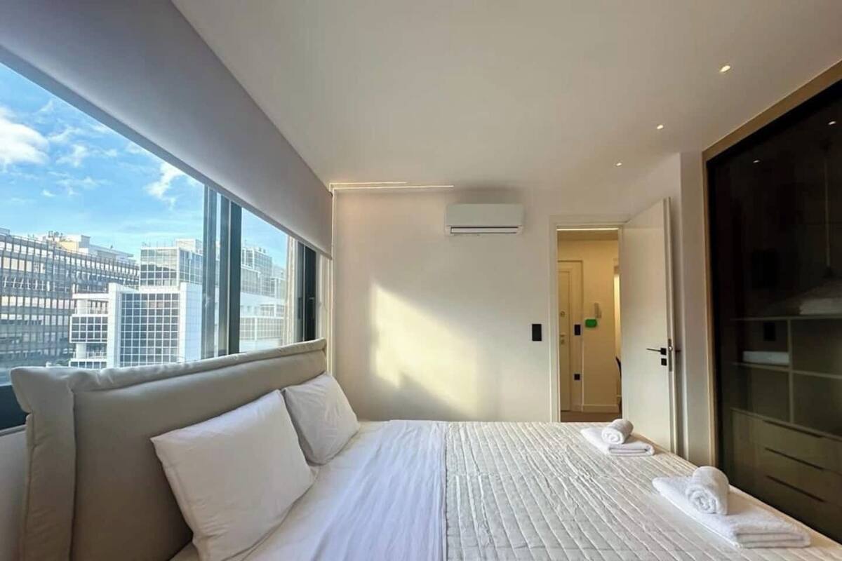 Une chambre d’hôtel avec un grand lit, une vue sur la ville et une porte donnant accès à la salle de bain.