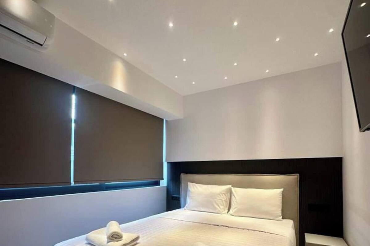 Une chambre d  ’hôtel moderne dotée d’un grand lit, d’une table de chevet, d’un téléviseur à écran plat et d’une fenêtre avec des stores.