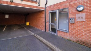 A building with a brick facade, a glass door entrance, and a sign indicating apartments 14-45.