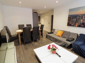 Un salon moderne comprenant un coin repas, un canapé, une table basse agrémentée d’une plante et une télécommande.
