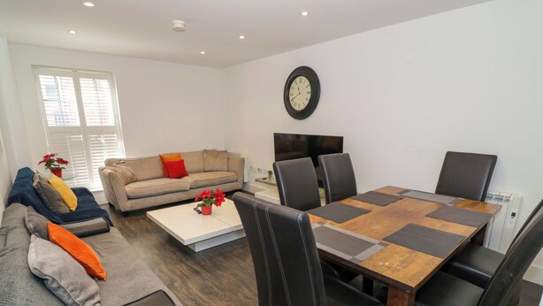 A modern living room with a sofa, coffee table, dining table, and chairs.