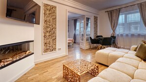 A modern living room with a fireplace, a sofa, a dining area, and a view of the outdoors. - Cozy 1-bedroom apartment in the City Center in București (București)