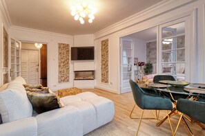 Ein modernes Wohnzimmer mit einer Couch, Sesseln, einem Kamin und einem Essbereich.