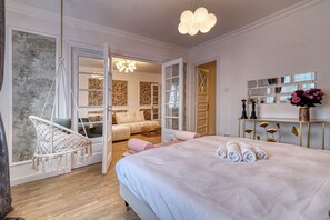 Ein Schlafzimmer mit einem Bett, einem Hängesessel, einer Couch und einem Spiegel an der Wand.