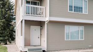 Un immeuble résidentiel de deux étages, avec une porte d’entrée portant l’inscription « 3A », un petit balcon et une antenne parabolique.