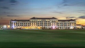 A large, multi-story hotel with a symmetrical facade, multiple balconies, and a well-lit entrance. - The Mirage VIP At Habtoor polo Resort  (Dubai)