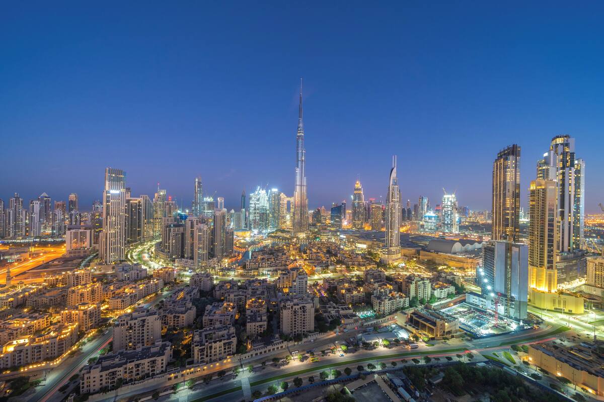 A cityscape with a prominent skyscraper, dense urban development, and illuminated streets.