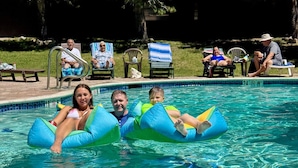 Una piscina con flotadores, sillas de descanso y una vista despejada del borde.