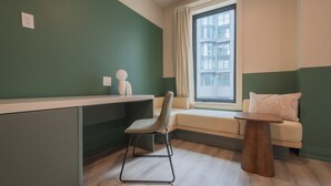 A room with a desk, chair, window, and a small table. - Hotel Beebop (Toronto)