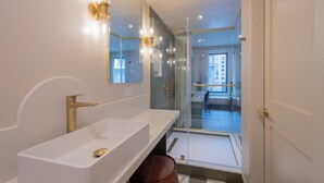 A modern bathroom with a large mirror, a white sink, and a glass shower enclosure. - Hotel Beebop (Toronto)