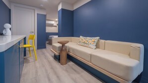 A modern living area with a sofa, a small round table, a yellow chair, and a white countertop. - Hotel Beebop (Toronto)