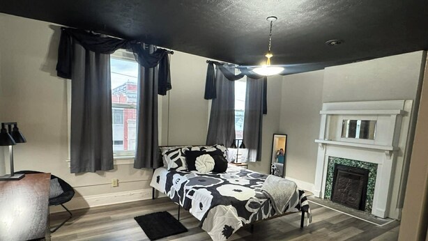 A bedroom with a bed, a mirror, a fireplace, and a window with curtains. - Cozy 1-bedroom apartment in charming Shepherdsville with AC (Shepherdsville)