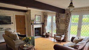 A cozy living room with a fireplace, a sofa, a chair, and a television. - Countryside Farmhouse - Glasgow - Sleeps 6 (Eaglesham)