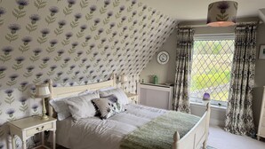 A bedroom with a bed, bedside tables, a lamp, a radiator, and a window with curtains. - Countryside Farmhouse - Glasgow - Sleeps 6 (Eaglesham)