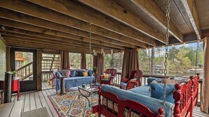 Una terraza de madera con una cama, sillas y una mesa.