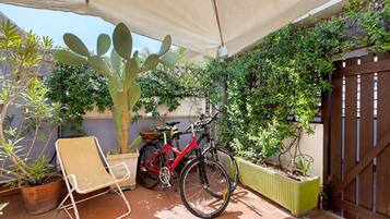 Une terrasse avec une chaise, deux vélos et un cactus.