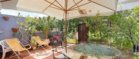 A glass-top table with chairs and an umbrella in a patio area.