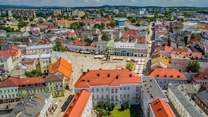 An aerial view of a cityscape with a prominent building with a red roof in the foreground, surrounded by other buildings with various roof colors. - ONRest Hostel (Kielce)