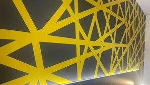 A wall with a geometric yellow pattern and a flat-screen TV. - ONRest Hostel (Kielce)