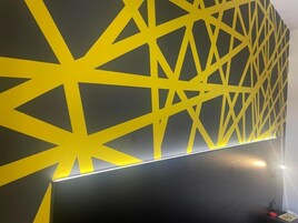 Pared con un diseño geométrico amarillo y un televisor de pantalla plana.