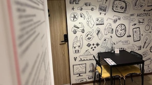 A room with a wall decorated with various doodles, a table with a chair, and a door in the background. - ONRest Hostel (Kielce)