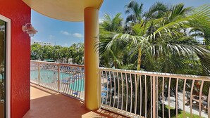 A balcony with a view of a pool and palm trees. - Crystal Palms 207 (Treasure Island)