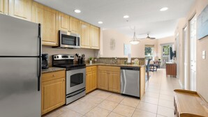 A kitchen with wooden cabinets, stainless steel appliances, and a tiled floor. - Crystal Palms 207 (Treasure Island)