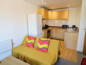 Une petite chambre comprenant un lit, une kitchenette et un réfrigérateur.