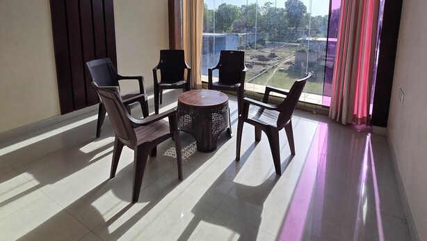 A spacious room with a ceiling fan, large windows with curtains, and a view of a landscape. - Hotel Siddhi Palace (Ayodhya)