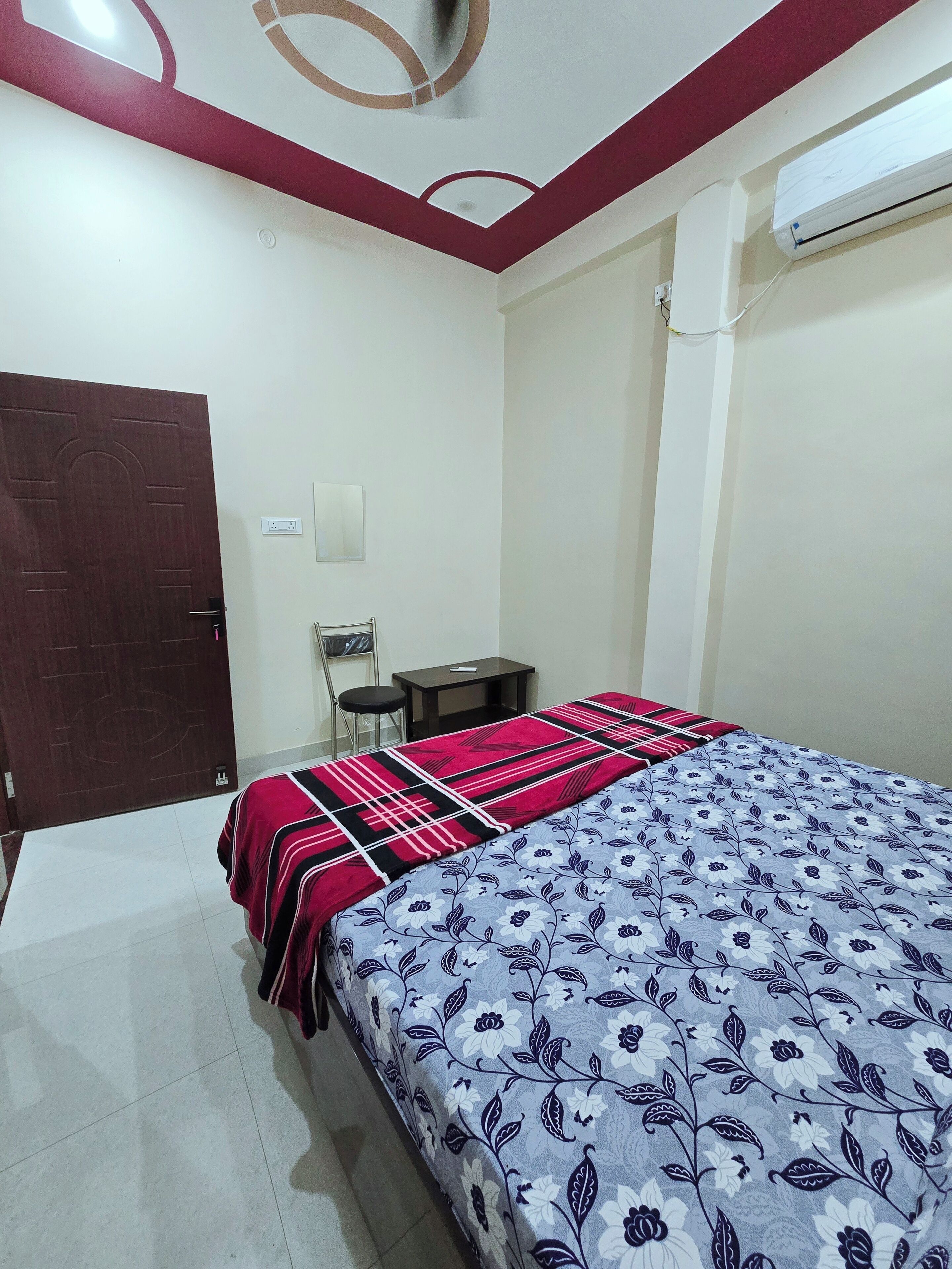 Quarto com cama, escrivaninha, cadeira, guarda-roupa e ar condicionado.