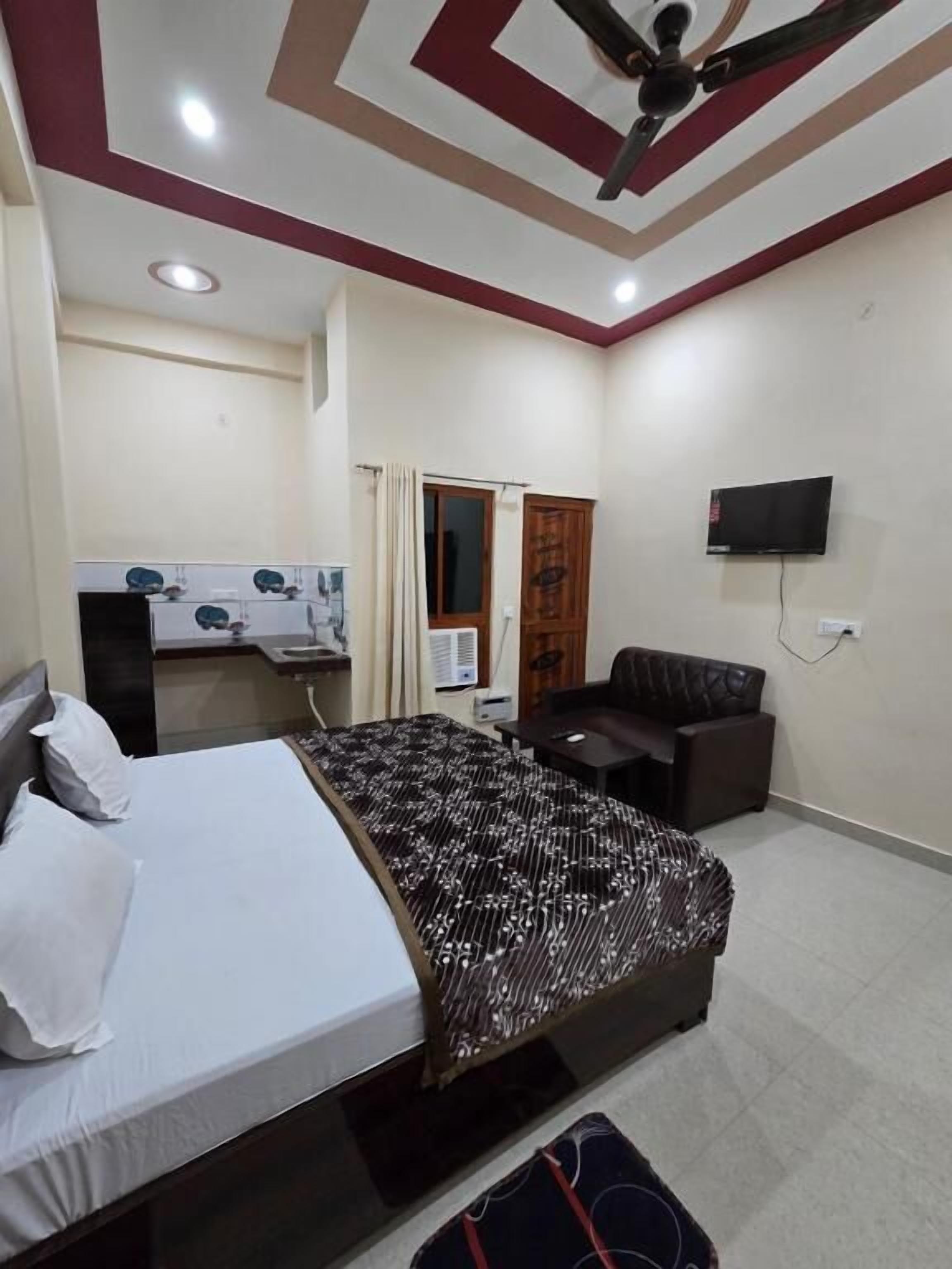 Una habitación de hotel con cama, escritorio, silla, televisor y ventilador de techo.