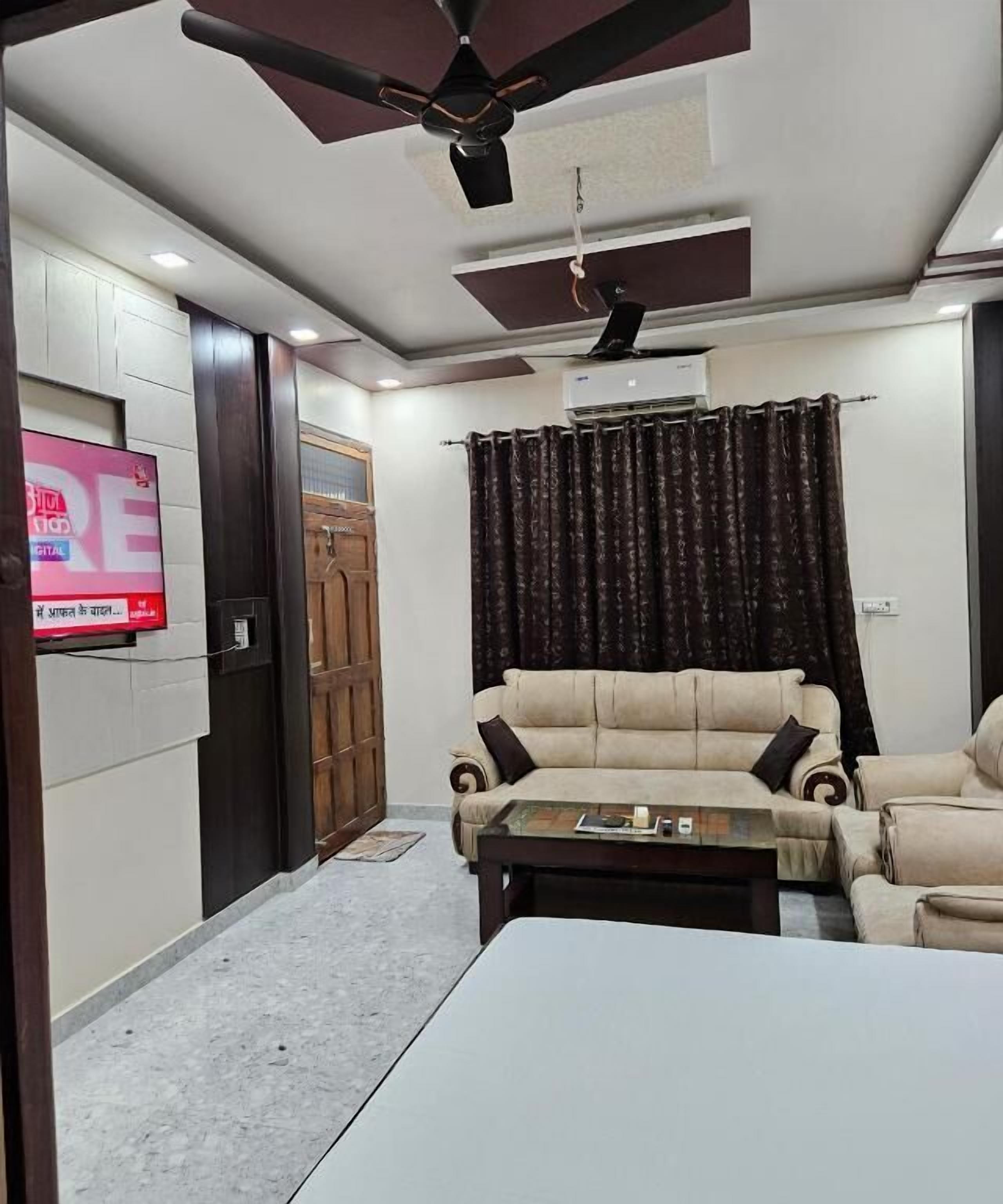 A living room with a sofa, a coffee table, a TV, a ceiling fan, and an air conditioning unit.