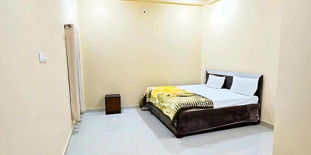 Un dormitorio con cama, mesita de noche y lámpara de pared.