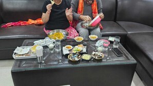 A dining area with a sofa and a glass-top table set with various dishes and condiments. - Hotel Siddhi Palace (Ayodhya)
