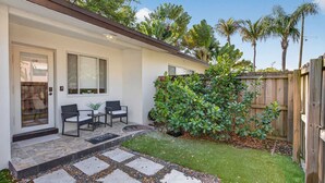 Una casa con patio, un pequeño jardín y valla de madera.