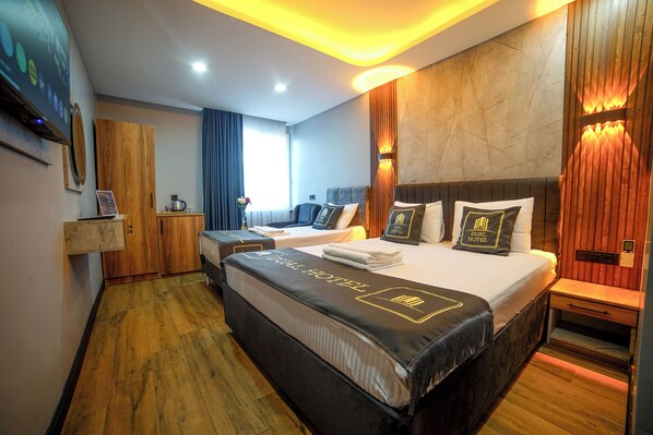 Ein Hotelzimmer mit einem großen Bett, einem Schreibtisch, einem Stuhl, einem Fernseher und einem Holzboden.