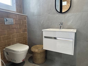A bathroom with a toilet, a sink, a mirror, and a trash bin. - Lake Villa 3 Bedrooms (Grombalia)