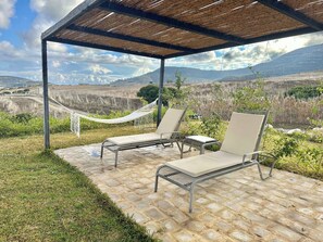 A covered outdoor seating area with two lounge chairs and a hammock, overlooking a mountainous landscape. - Lake Villa 3 Bedrooms (Grombalia)