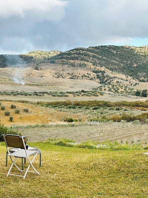 A chair in a grassy field with a hilly landscape in the background. - Lake Villa 3 Bedrooms (Grombalia)