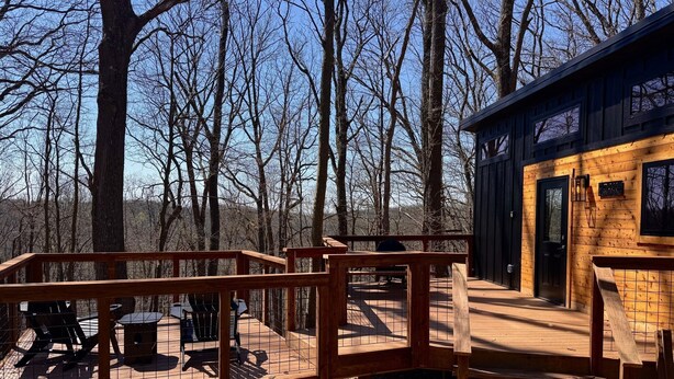 Une terrasse en bois avec des meubles d’extérieur, un espace délimité par une clôture et un chalet doté d’une porte et de fenêtres.