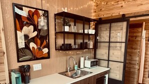 Une cuisine moderne avec des meubles en bois, un évier encastré, un four à micro-ondes et une machine à café.