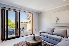 A modern living room with a sofa, a coffee table, and a painting on the wall.
