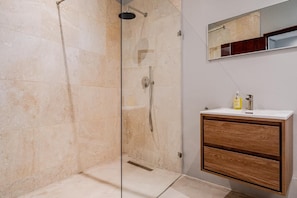 A bathroom with a glass-enclosed shower, a wooden vanity, and a mirror above the sink.