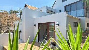 Una casa moderna con una veranda in legno, un ingresso con porta a vetro e un'ampia finestra.