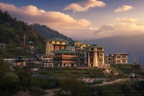 A multi-story hotel with balconies, situated on a hillside with a view of the surrounding landscape. - Norbu Lingka Resort (Trongsa)