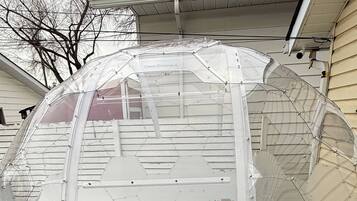 A transparent geodesic dome structure with a green artificial turf base, attached to a building.