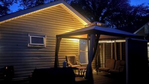 A covered outdoor area with a table and chairs, a small window, and a door. - Quiet Heritage Bungalow Entire Home Geodome (Edmonton)