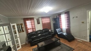 A living room with a sofa, a recliner, a coffee table, and a door with a mirror. - Quiet Heritage Bungalow Entire Home Geodome (Edmonton)