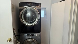 A laundry room with two stacked washers and dryers, a window, and a door. - Quiet Heritage Bungalow Entire Home Geodome (Edmonton)